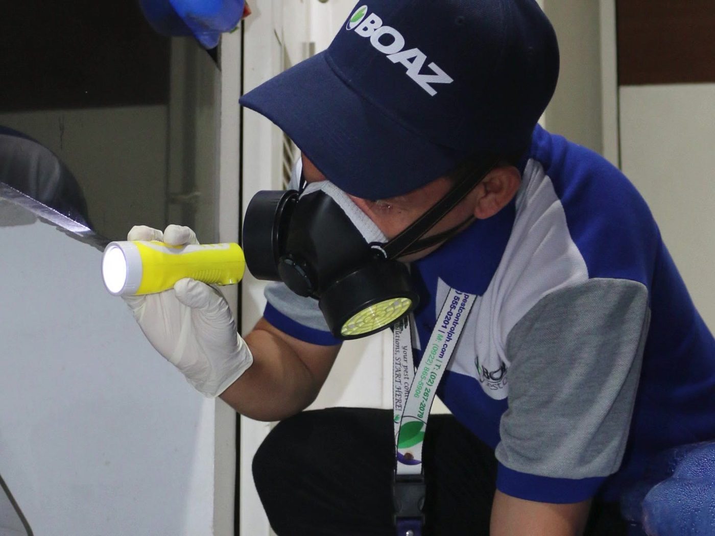 BOAZ technician inspecting a service area with a flashlight